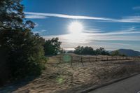 a sun shines brightly behind a wire fence in this photo from inside a car