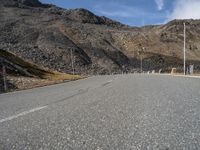 a man riding a bicycle on the road in the mountains outside a gate in front of a mountain