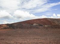 the lone horse is standing in front of some colorful hills and hills with scattered rocks and rock strewn on top