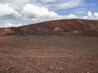 the lone horse is standing in front of some colorful hills and hills with scattered rocks and rock strewn on top