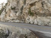 a person is riding on a motorcycle along a mountain road with graffiti on it's side