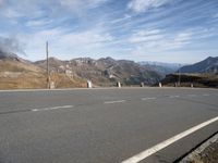 the mountains are near the empty empty road in the middle of the photo and smoke is flying in the air