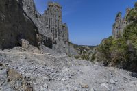 a lone path through a canyon with rock formations in the background with green and blue sky