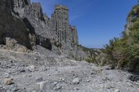 a lone path through a canyon with rock formations in the background with green and blue sky