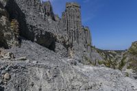 a lone path through a canyon with rock formations in the background with green and blue sky