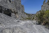 a lone path through a canyon with rock formations in the background with green and blue sky