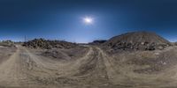 a fish eye lens view of a deserted dirt road by a mountain range at sunset