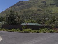 a stop sign and street in a residential neighborhood near mountains are seen here, with a house on top