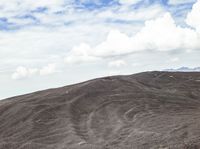 a person rides on a bike up a mountain side slope in the desert, with hills behind them