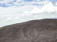 a person rides on a bike up a mountain side slope in the desert, with hills behind them