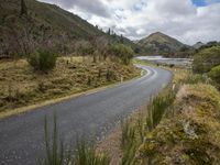 a road leading through an area with a lot of mountains in the background, and a highway is running through the field