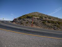 a curved road and mountain against a blue sky and a partly cloudy sky on the right