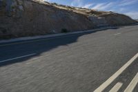 two people riding on a motorcycle down a mountainous road in the mountains near a hillside