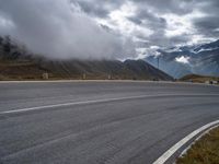 a car driving down a mountain road under a cloudy sky on a rainy day near a town