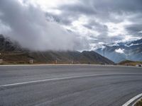 a car driving down a mountain road under a cloudy sky on a rainy day near a town