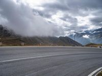 a car driving down a mountain road under a cloudy sky on a rainy day near a town