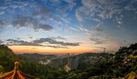 a tall pagoda is overlooking the beautiful mountain landscape at dusk in this photograph, the sky and buildings have a bright light