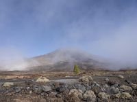 a road near the mountain side in the foggy sun day, and on the opposite bank are hills