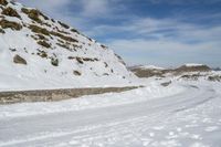 a person in the snow with skis looking at some big rocks and a hill