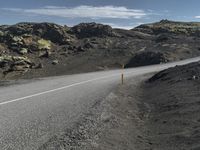 a motorcycle is driving down a mountain road in front of a few rocks and grass