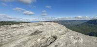 a very big rocky outcropping in the mountains overlooking an ocean and sky