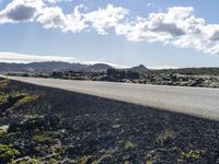 a road with rocks along it and the sky in the background with some clouds overhead