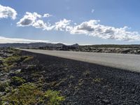 a road with rocks along it and the sky in the background with some clouds overhead