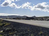 a road with rocks along it and the sky in the background with some clouds overhead