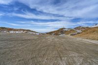 a paved area with a hill on each side and some snow around it and the ground is littered with dirt