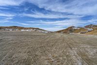 a paved area with a hill on each side and some snow around it and the ground is littered with dirt