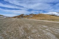 a paved area with a hill on each side and some snow around it and the ground is littered with dirt