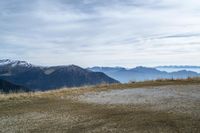 a person riding a bike in the distance in the mountains with mountain range and mountain peaks