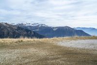 a person riding a bike in the distance in the mountains with mountain range and mountain peaks