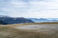 a person riding a bike in the distance in the mountains with mountain range and mountain peaks