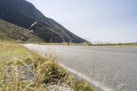 a motorcycle parked on a small mountain side road near mountains with no cars driving on it