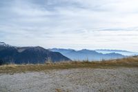 a person standing on the side of a hill watching mountains and lake from high up