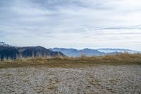 a person standing on the side of a hill watching mountains and lake from high up