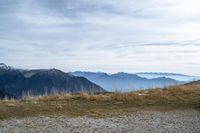 a person standing on the side of a hill watching mountains and lake from high up