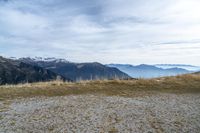 a person standing on the side of a hill watching mountains and lake from high up