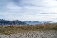 a person standing on the side of a hill watching mountains and lake from high up