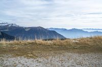 a person standing on the side of a hill watching mountains and lake from high up