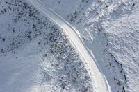 a trail in the snow leading a mountain side down to a slope covered in deep snow