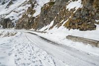 a person on skis riding on the snow road near mountain top with rocky cliff