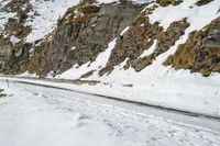 a person on skis riding on the snow road near mountain top with rocky cliff