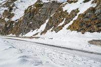 a person on skis riding on the snow road near mountain top with rocky cliff