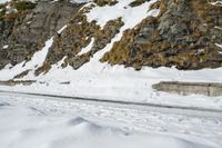 a person on skis riding on the snow road near mountain top with rocky cliff