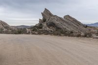 a dirt road that runs through the desert and rocky mountains with an umbrella and table