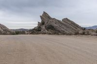 a dirt road that runs through the desert and rocky mountains with an umbrella and table