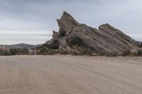 a dirt road that runs through the desert and rocky mountains with an umbrella and table