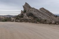 a dirt road that runs through the desert and rocky mountains with an umbrella and table